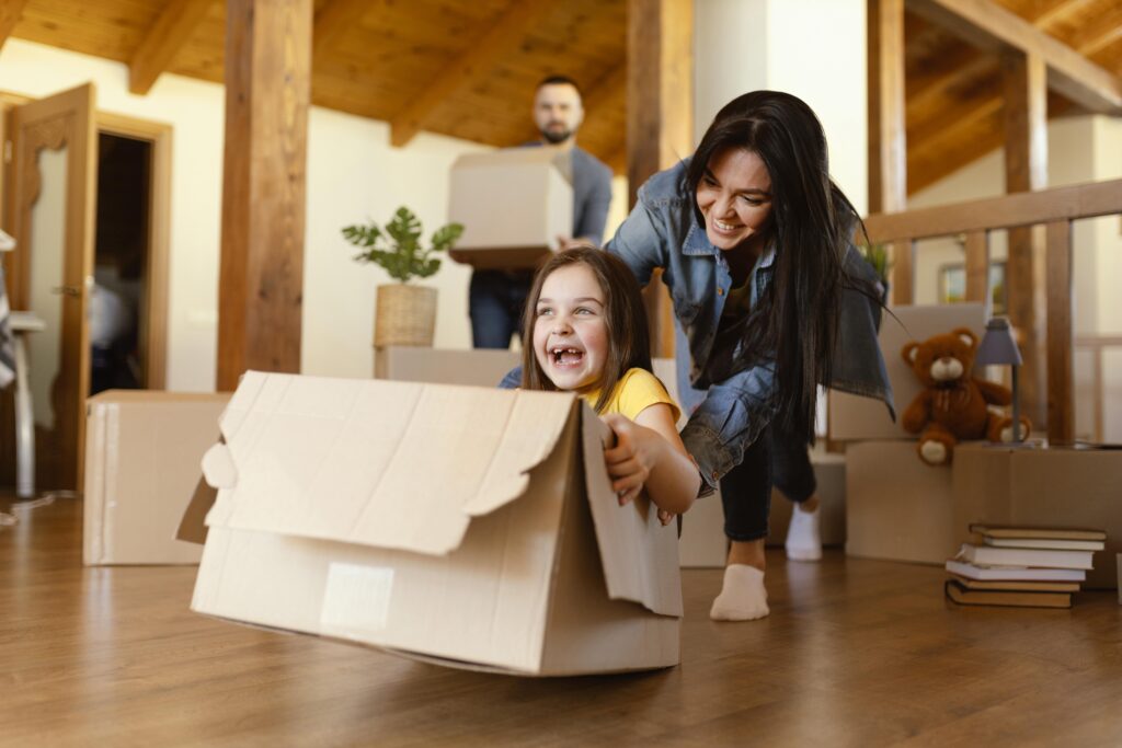 Parents packing boxes while kids play with their pet during a home relocation with Khimji Relocation Oman.